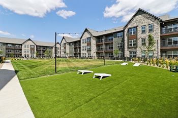 A green lawn with picnic tables in front of an apartment building